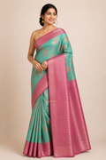 A woman modeling a green and pink silk saree with a matching blouse.