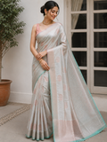 A woman models a light silver-gray silk saree.