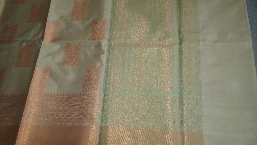 A close-up of a light beige fabric with metallic gold vertical stripes and peach-pink geometric motifs near the left side. 