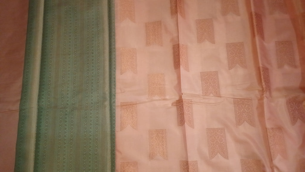 A close-up of a fabric textile laid flat, showing a mint green border with vertical woven detailing next to a light peach-pink body with repeating rectangular woven motifs. 