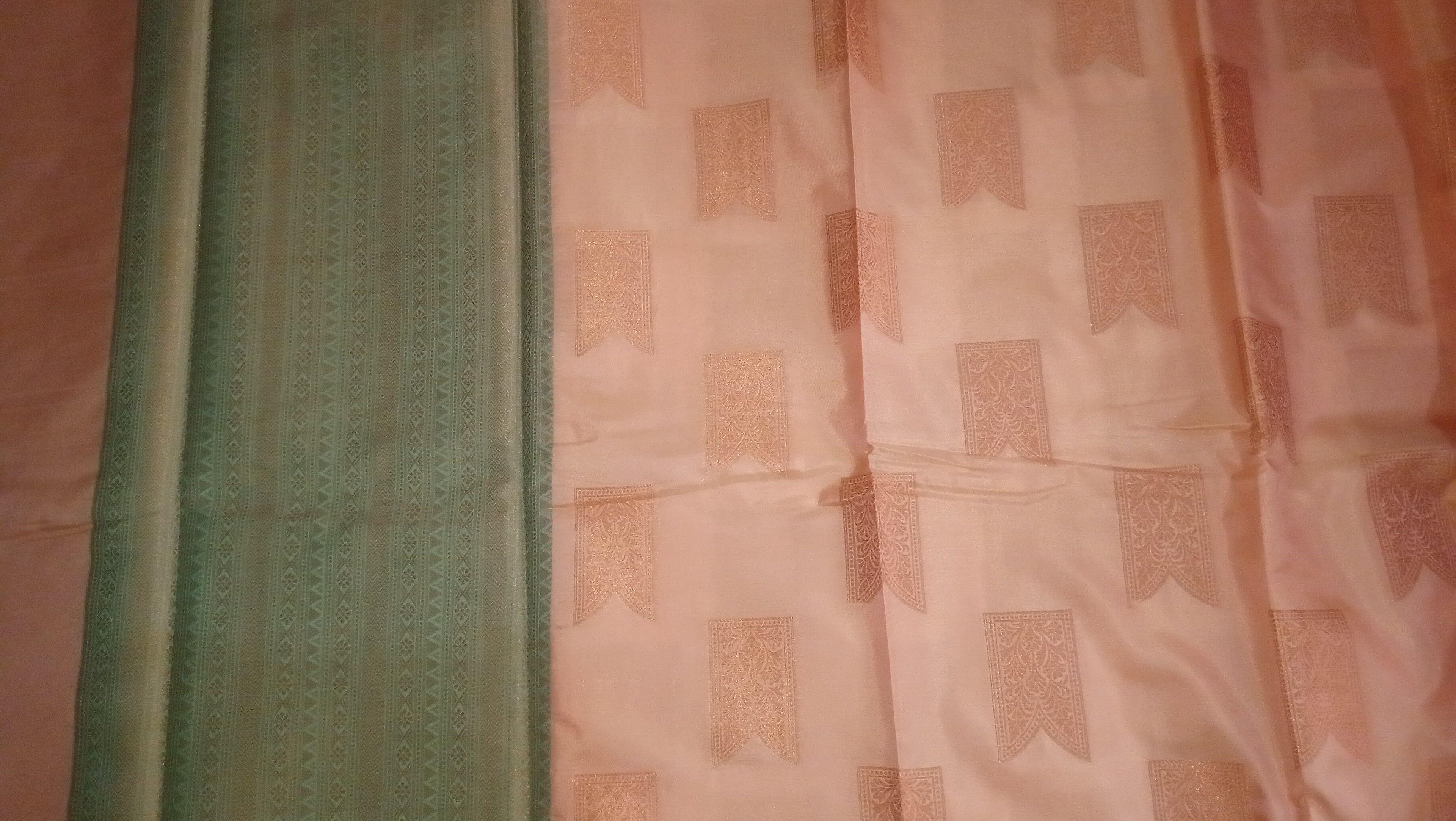 A close-up of a fabric textile laid flat, showing a mint green border with vertical woven detailing next to a light peach-pink body with repeating rectangular woven motifs. 